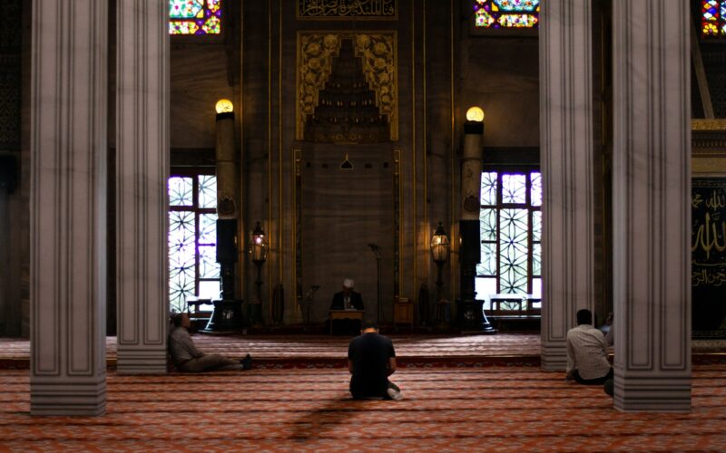 three men sitting inside mosque
