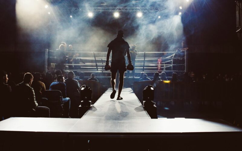man standing and walking going on boxing ring surrounded with people