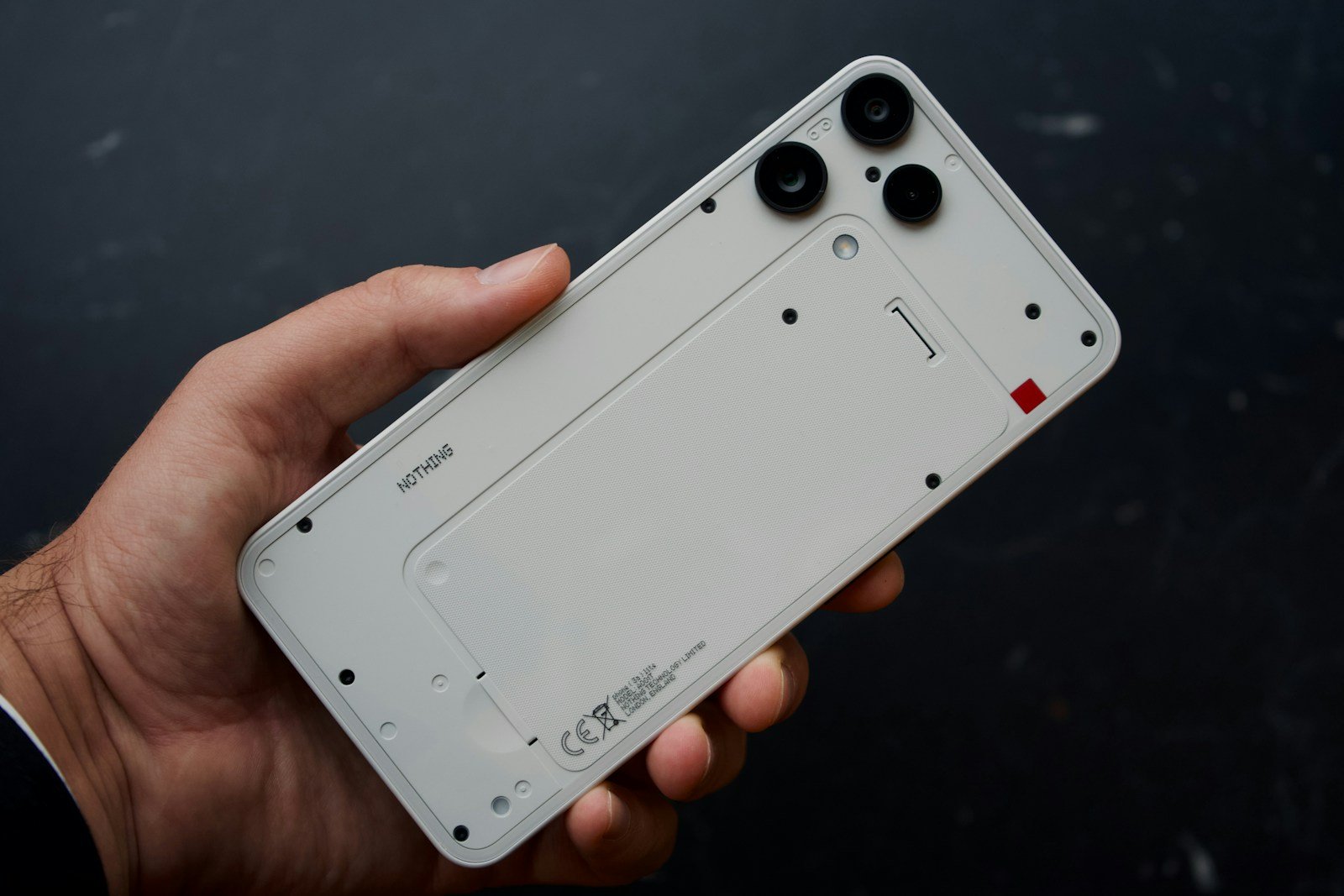 Hand holding a disassembled white smartphone
