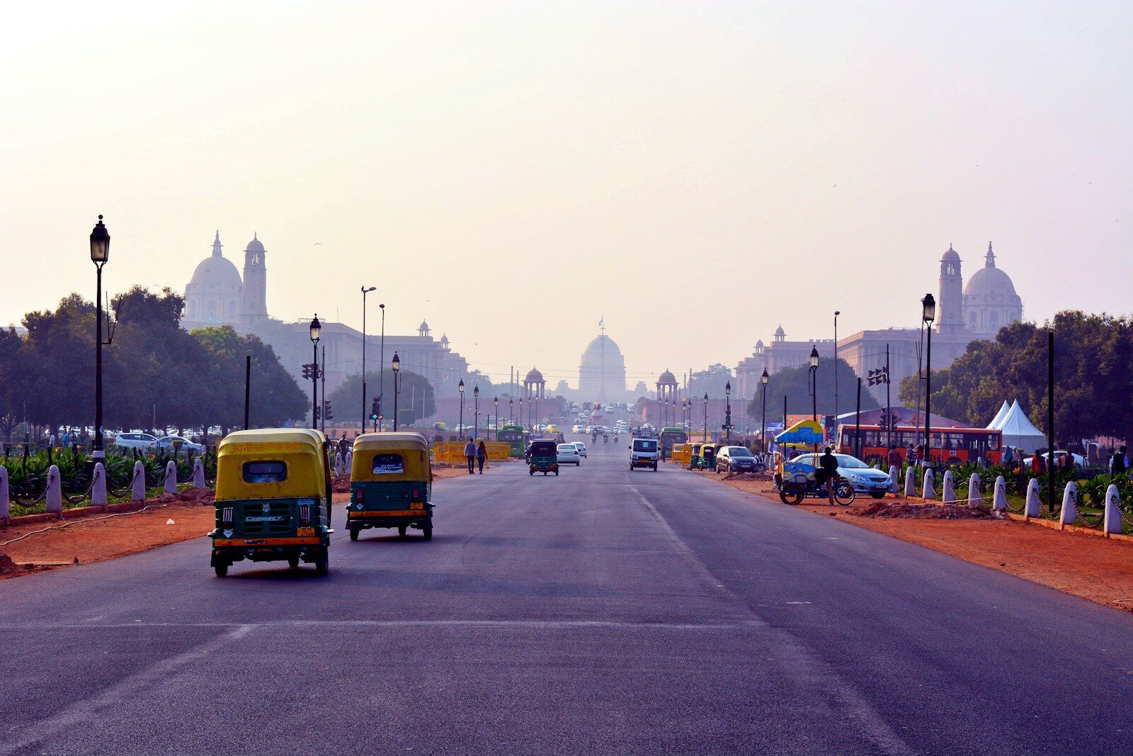 Auto rickshaws driving on a wide road toward the Rashtrapati Bhavan in New Delhi