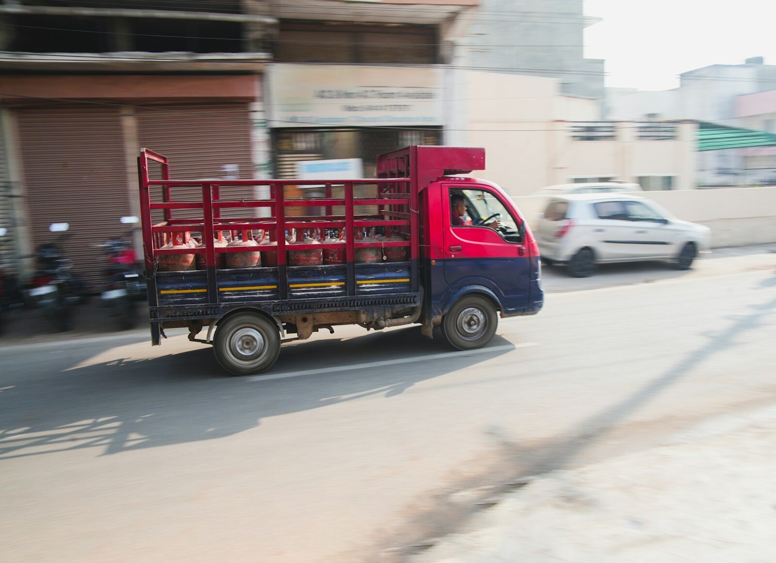 a red and blue truck driving down a street