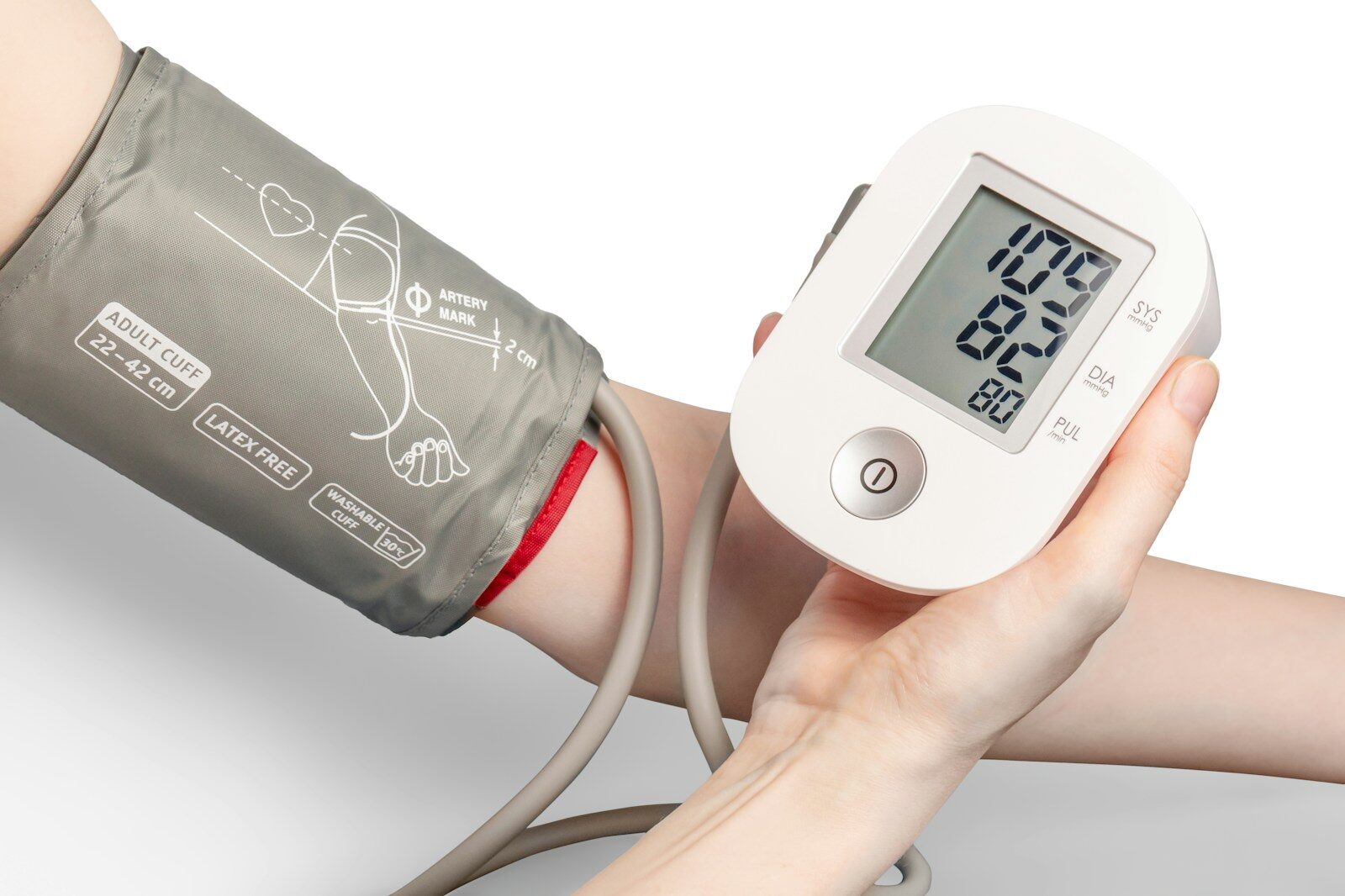A person using a digital blood pressure monitor with a grey cuff on their arm