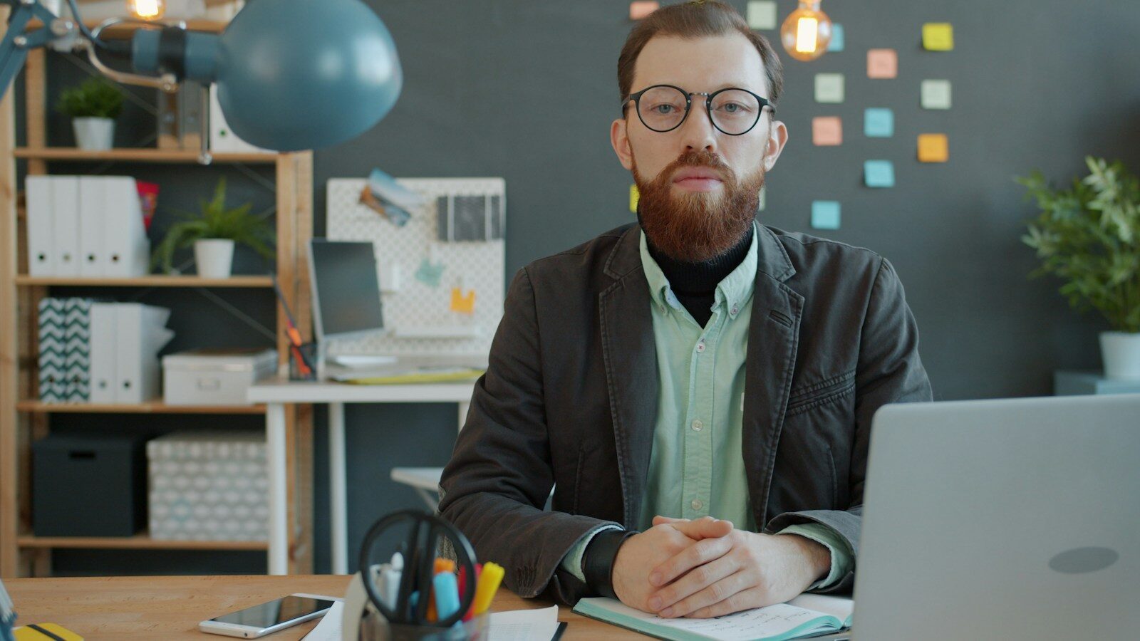 Man with beard and glasses sitting at desk