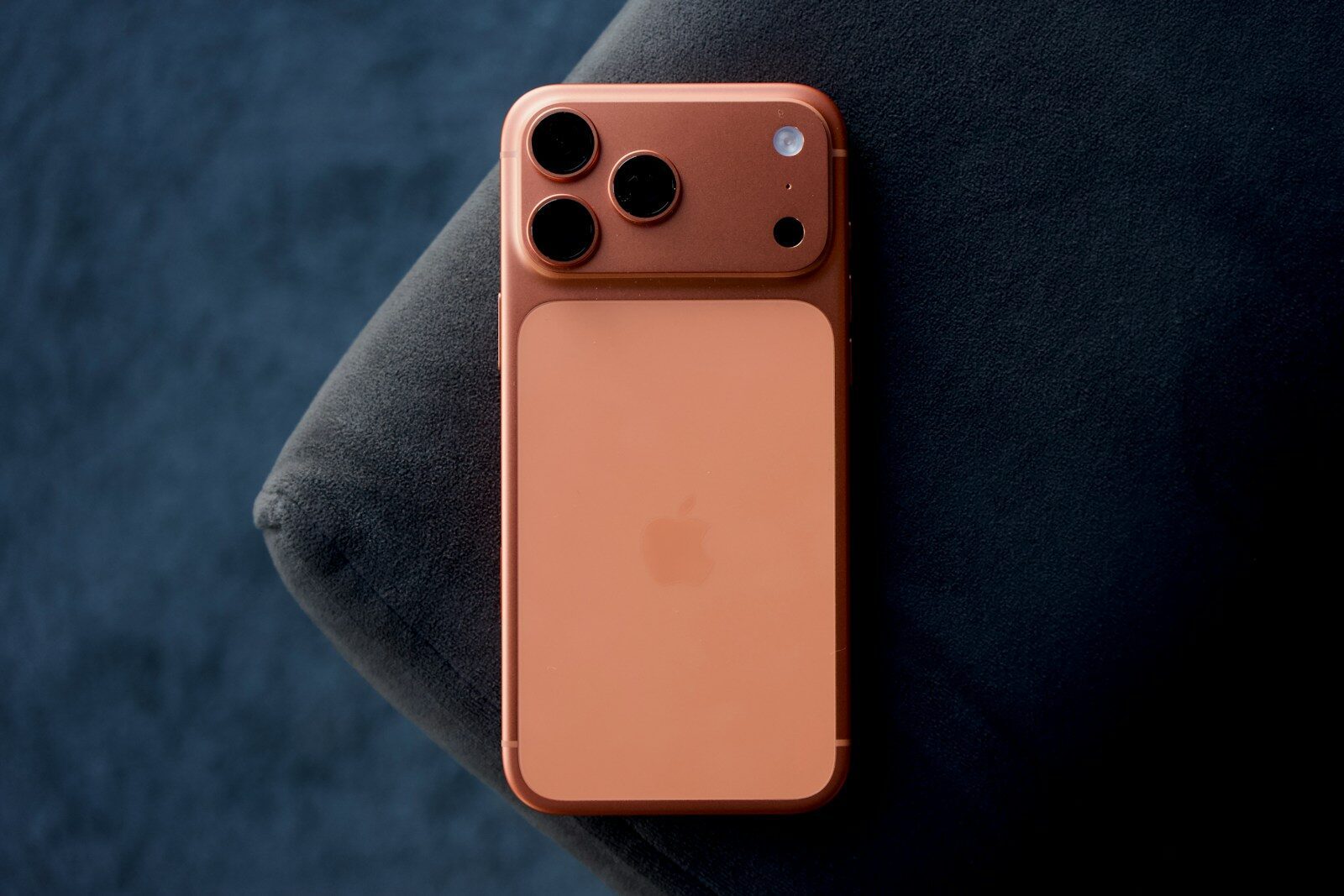 Rose gold smartphone resting on a dark blue surface