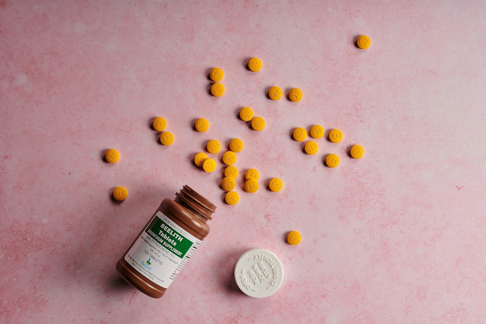 a bottle of pills sitting on top of a pink surface